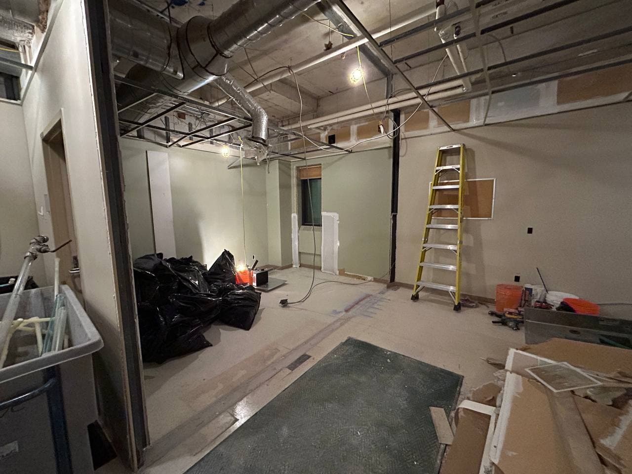 Technical work area with exposed ceiling systems, work lights, tools, and protected surfaces