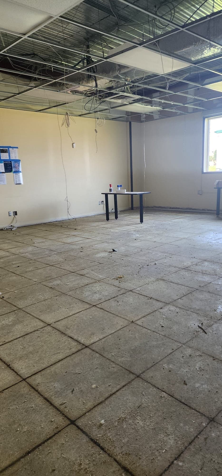 Cleared institutional room with suspended ceiling grid and wiring exposed