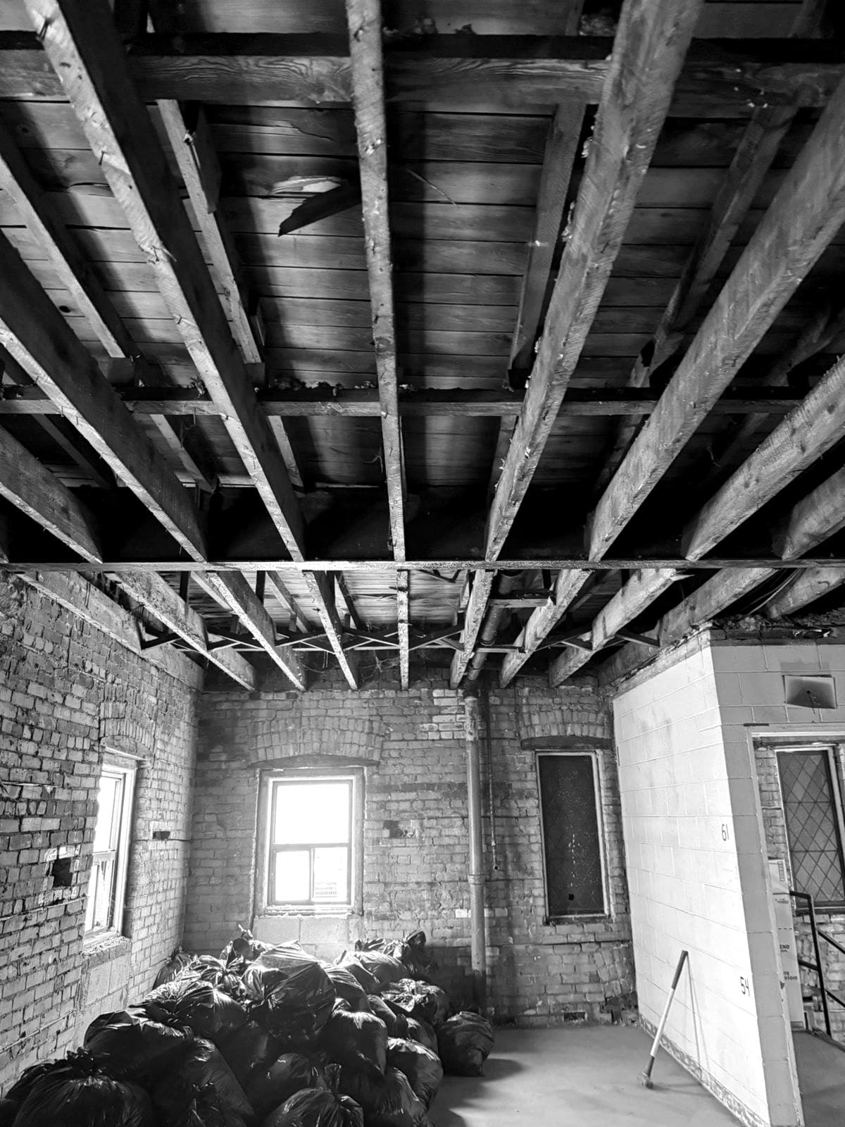 Interior construction area with exposed timber joists and brick walls